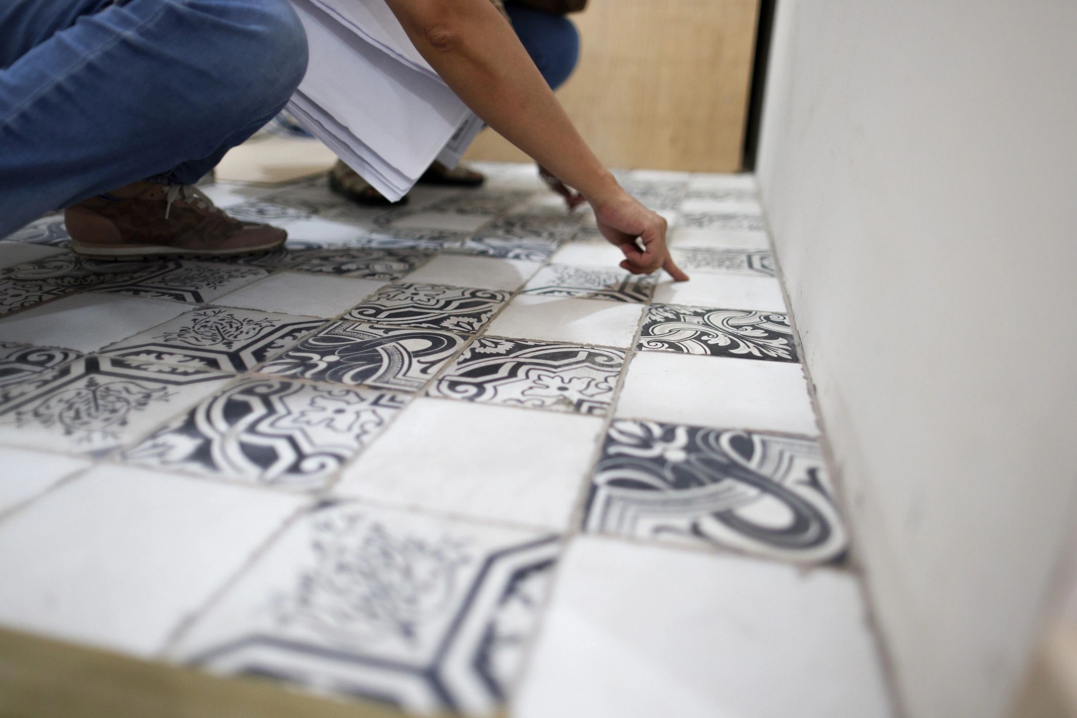 Person inspecting decorative floor tiles in showroom