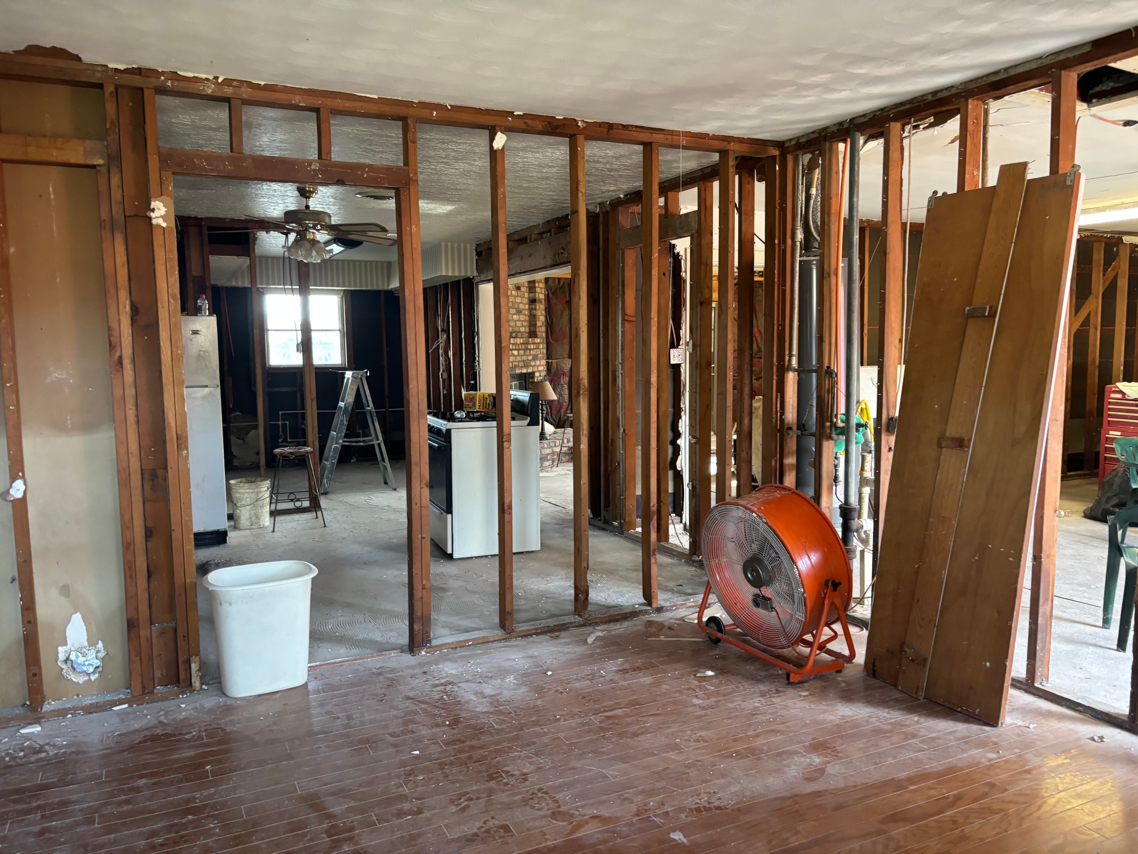 Interior renovation with exposed wood framing and orange industrial fan